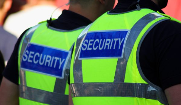 Image of two male security Guards with bright tops on.